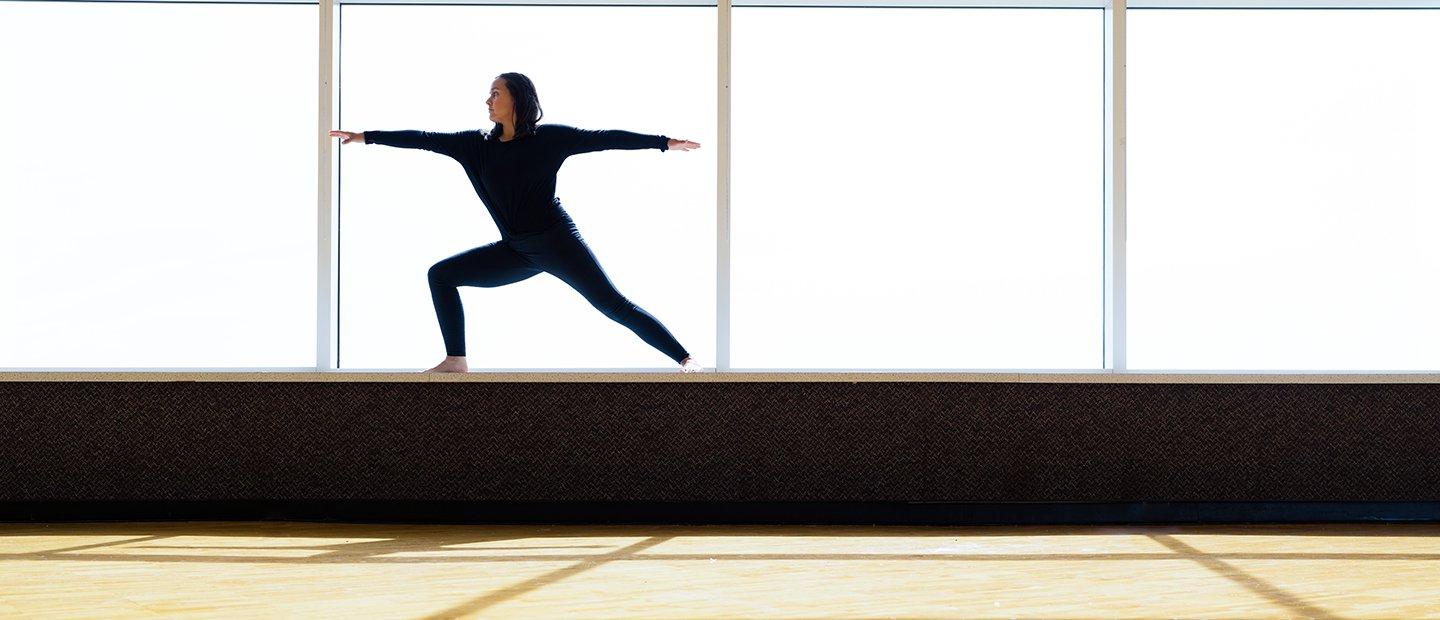 A person performing a yoga pose on the ledge of a window.